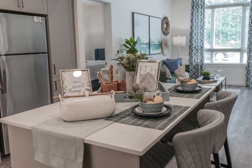 A modern kitchen island with place settings for two, decorative items, and a framed
