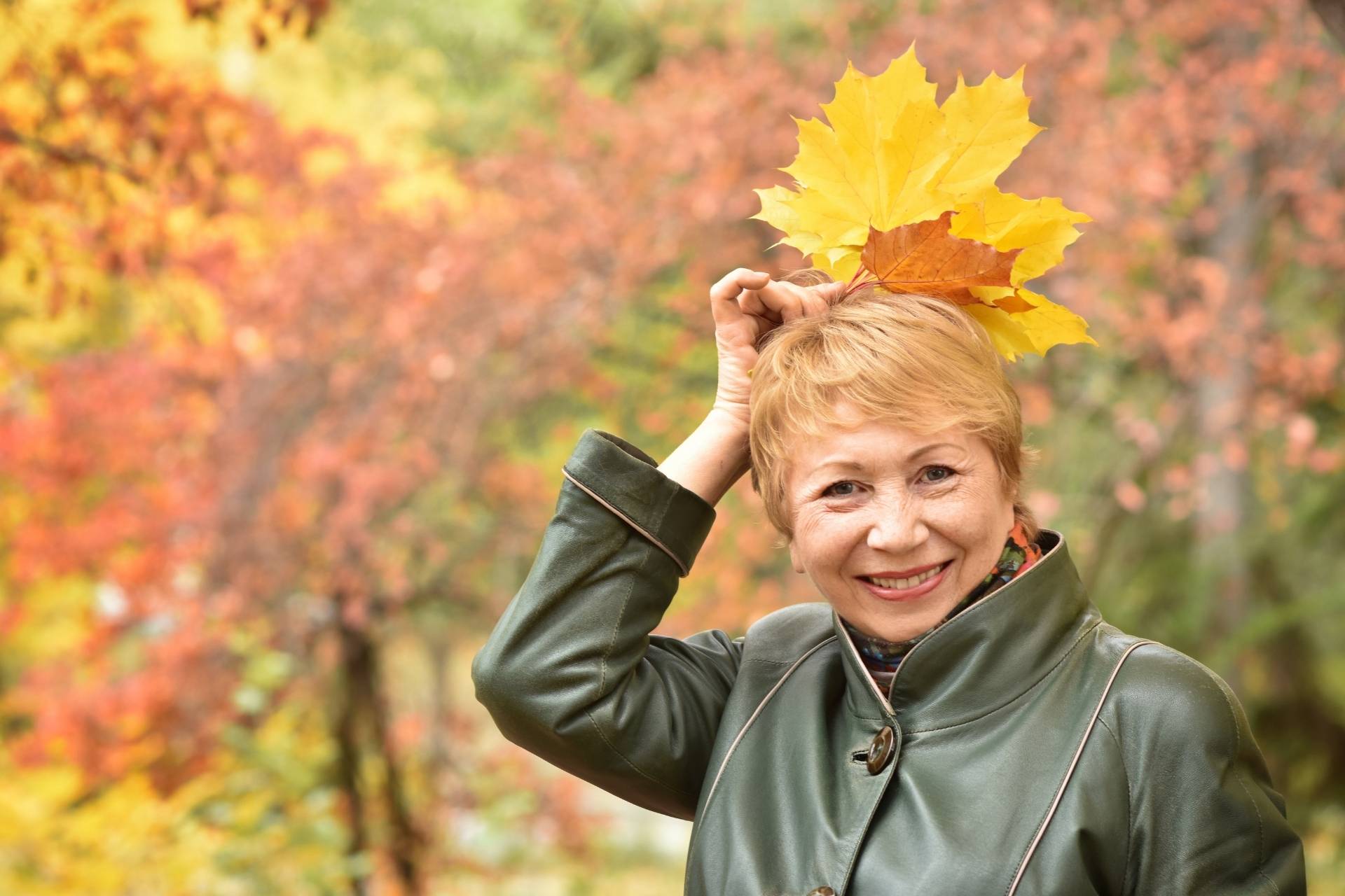 A senior woman enjoying the fall leaves.